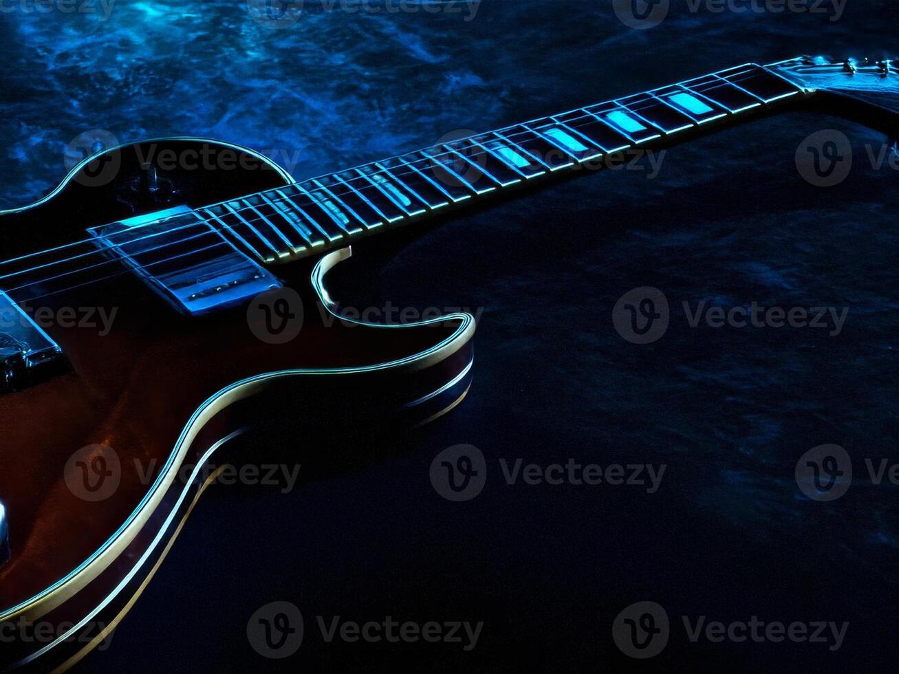 Electric guitar resting on a dark surface with blue backlight photo