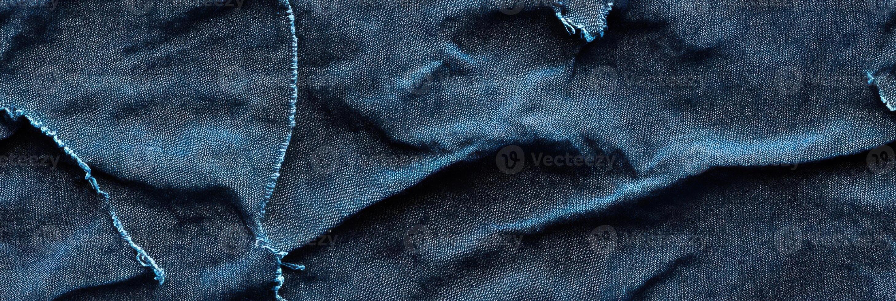 Close-up image of worn torn denim fabric texture with visible blue threads photo