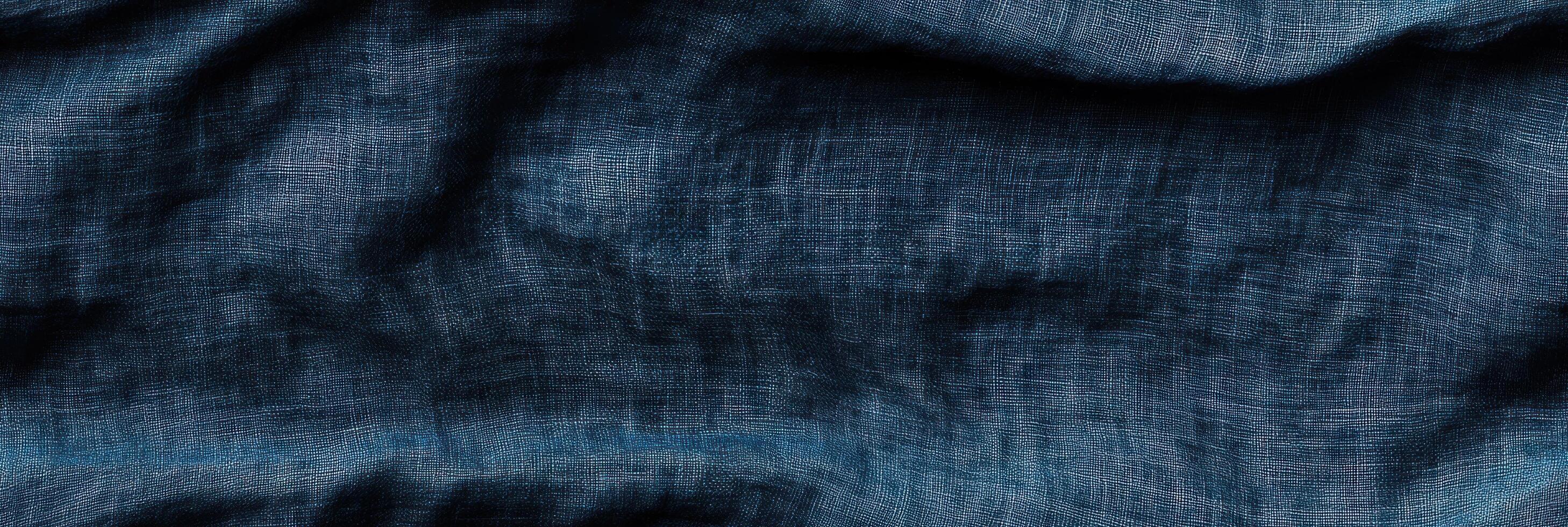 Dark frayed denim texture with wrinkles and folds in blue fabric photo