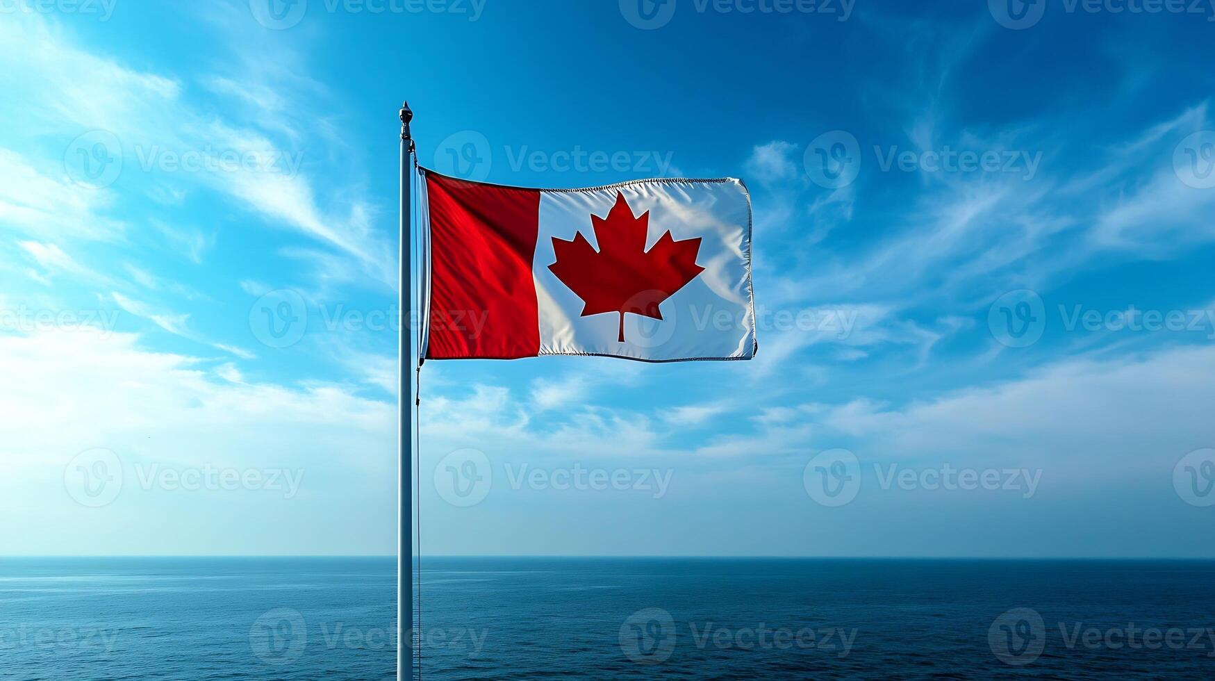 Canadian flag waving in the breeze against a vibrant blue sky and ocean horizon photo