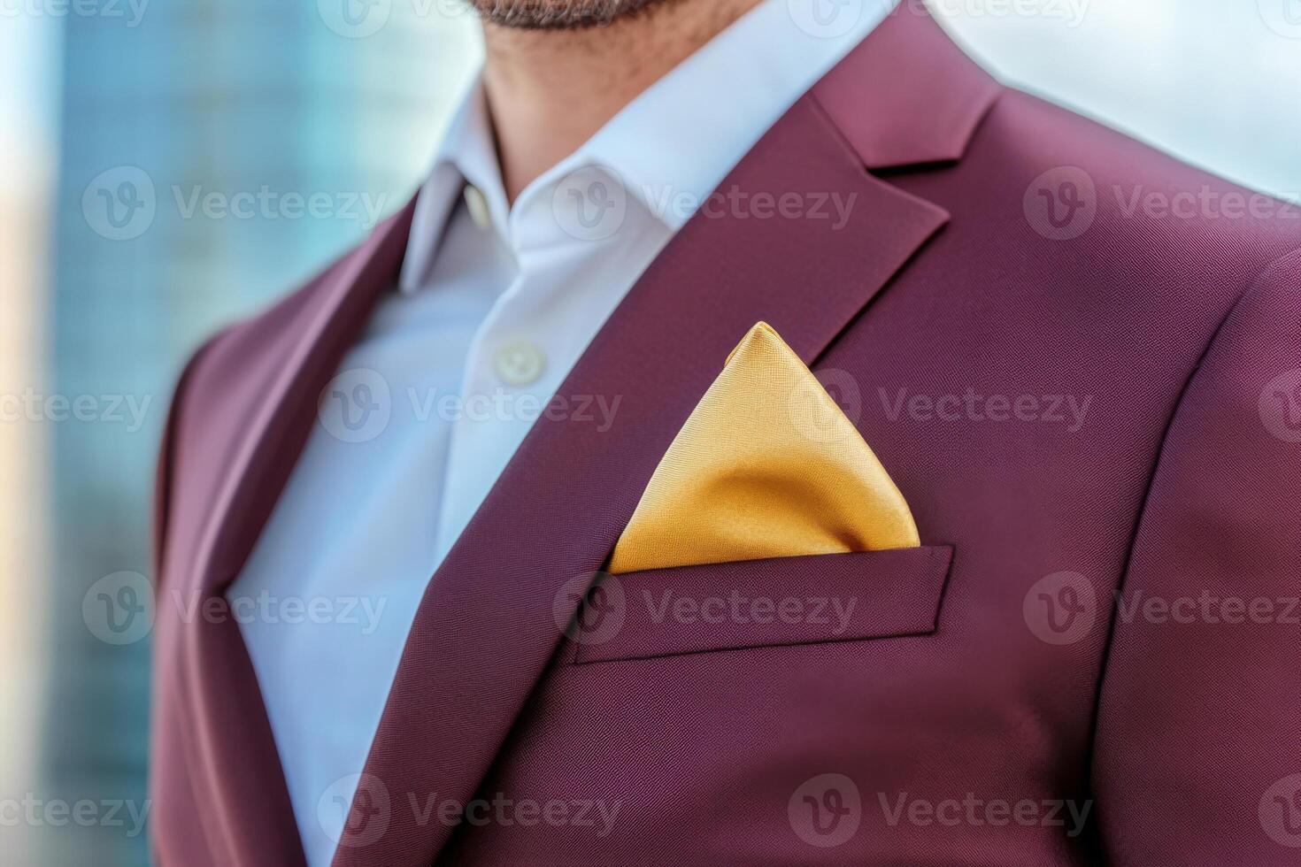 Confident man in burgundy suit with golden pocket square walks through urban landscape during the day photo