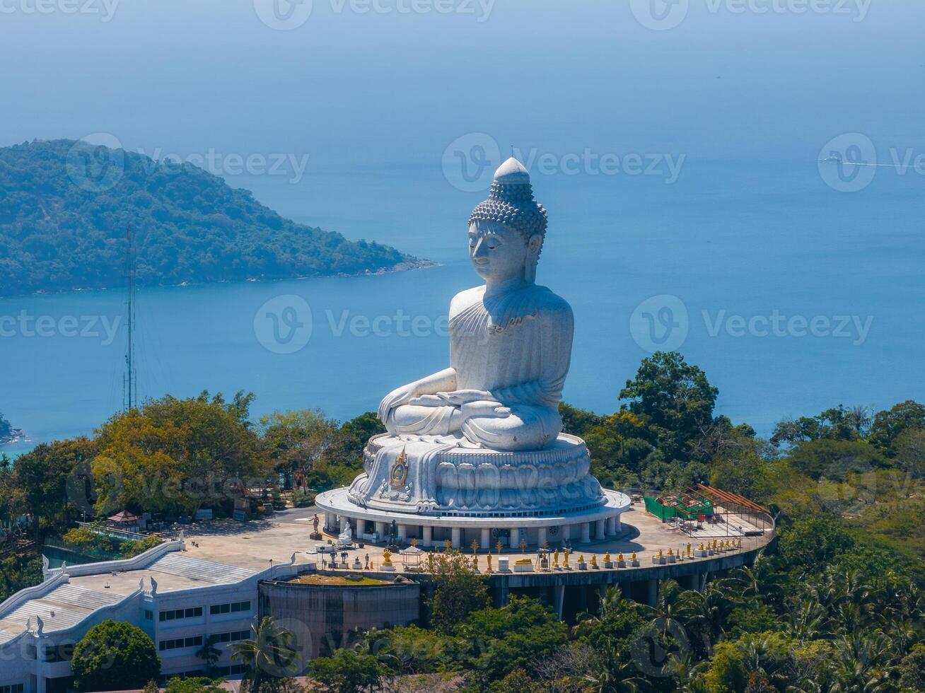 The iconic Big Buddha statue in Phuket, Thailand, surrounded by lush greenery, with views of the blue sea and distant islands in the background. photo
