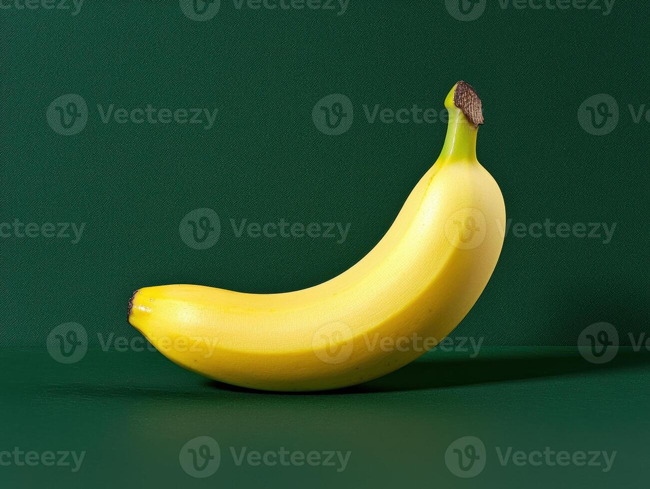 Single ripe yellow banana on a green background photo