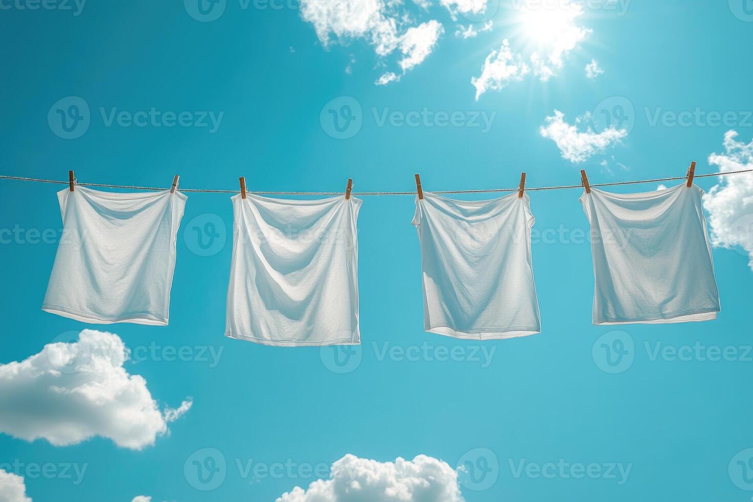 White laundry drying on clothesline under blue sky and sun photo