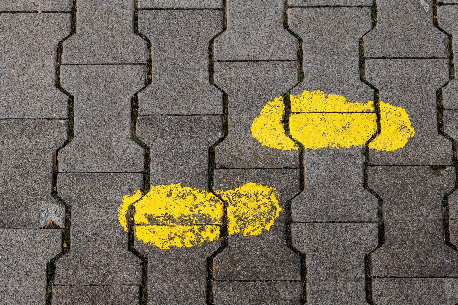 Unique yellow footprints painted on a gray brick pathway in an urban environment during daylight photo