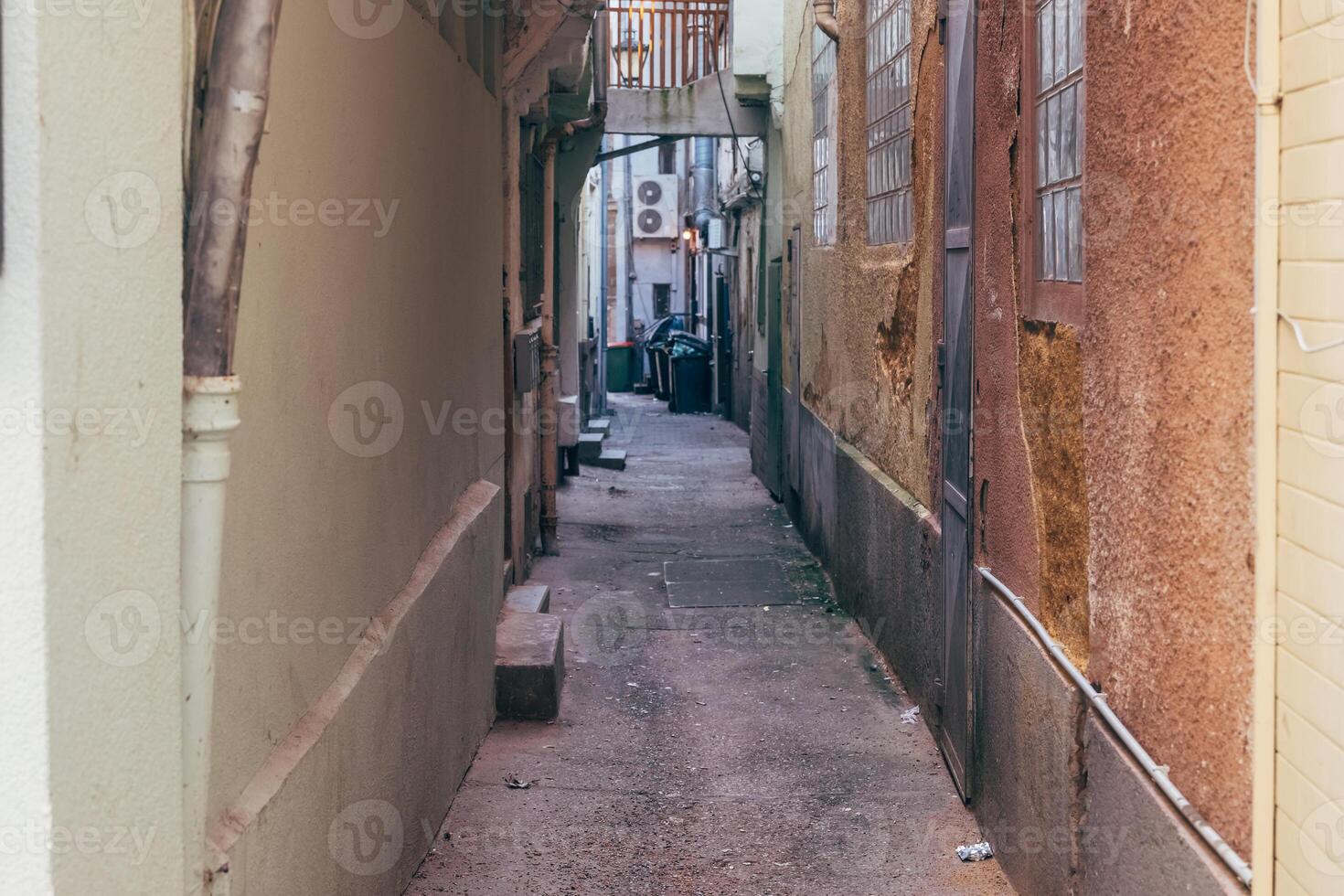 Narrow city alleyway with textured walls and scattered refuse during late evening hours photo