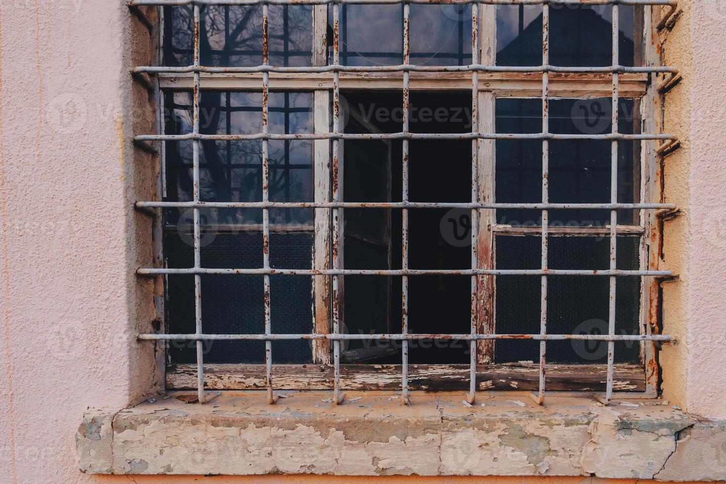 Rusty barred window on an old building showcasing wear and decay in an urban environment photo