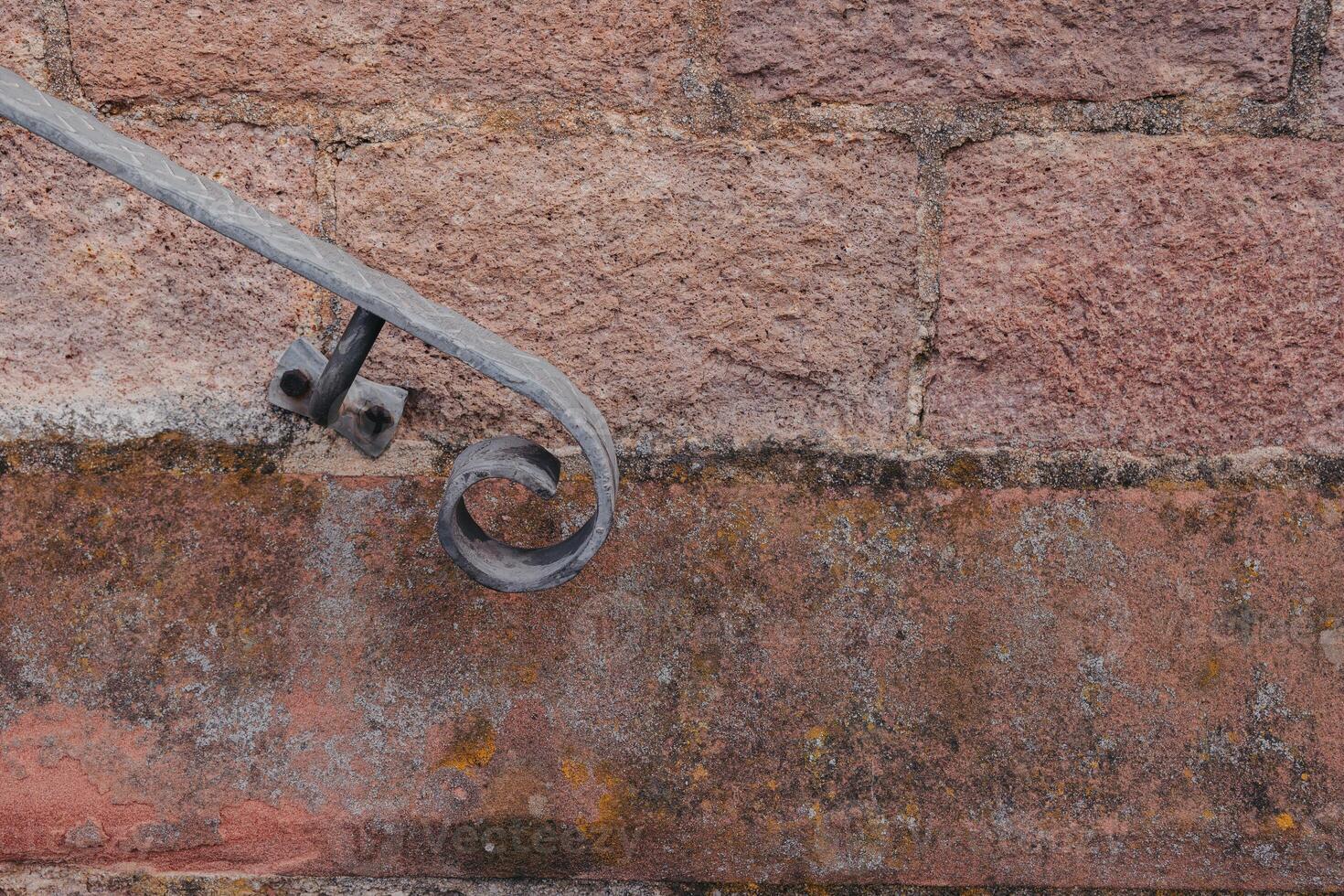 Wrought iron railing detail along rustic stone wall in historic town photo