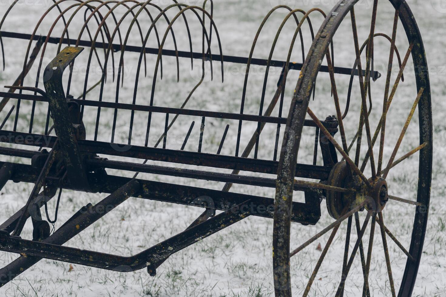Vintage agricultural rake resting on a snowy field during winter's quiet afternoon light photo