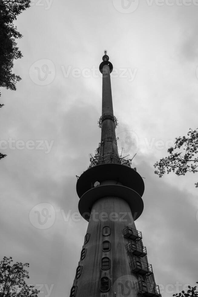 Tall communication tower rises against cloudy sky in urban area surrounded by trees photo
