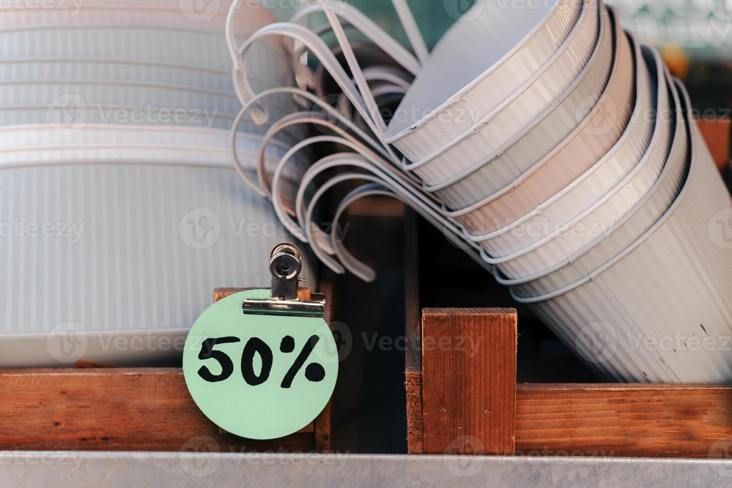 Discounts on disposable cups displayed in a wooden crate at a market stand during daytime photo