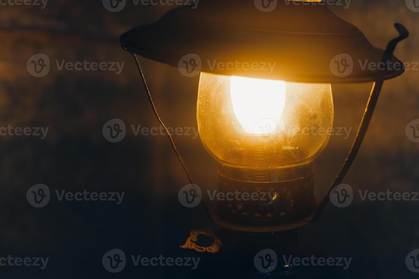 Warm glow of an antique lantern illuminating a rustic space during the evening photo