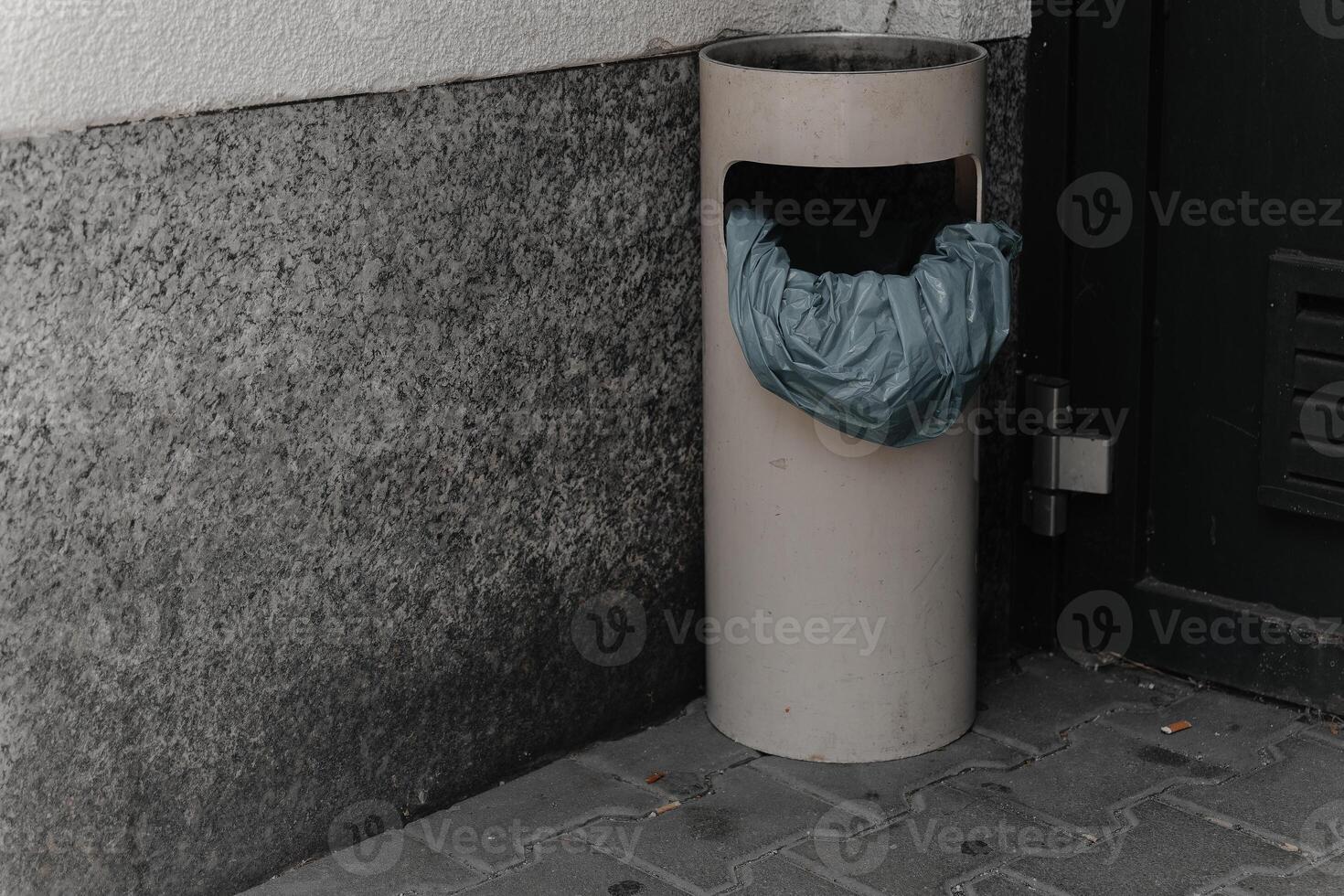 Unusual trash can with a plastic bag in an urban setting during daytime photo
