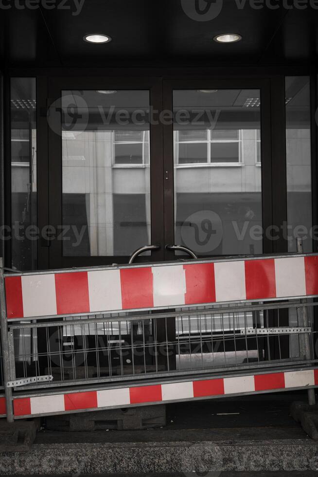 Barriers block entrance to modern building with glass doors during construction works in a busy urban area photo