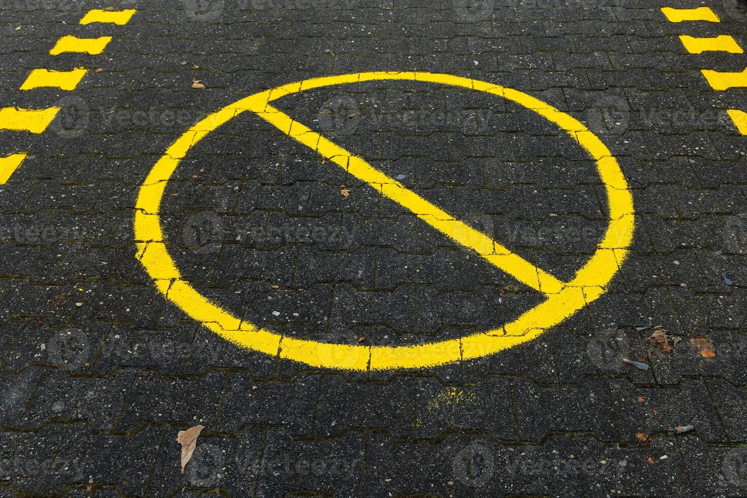 Yellow no parking sign on pavement prohibits vehicles from stopping in this area photo