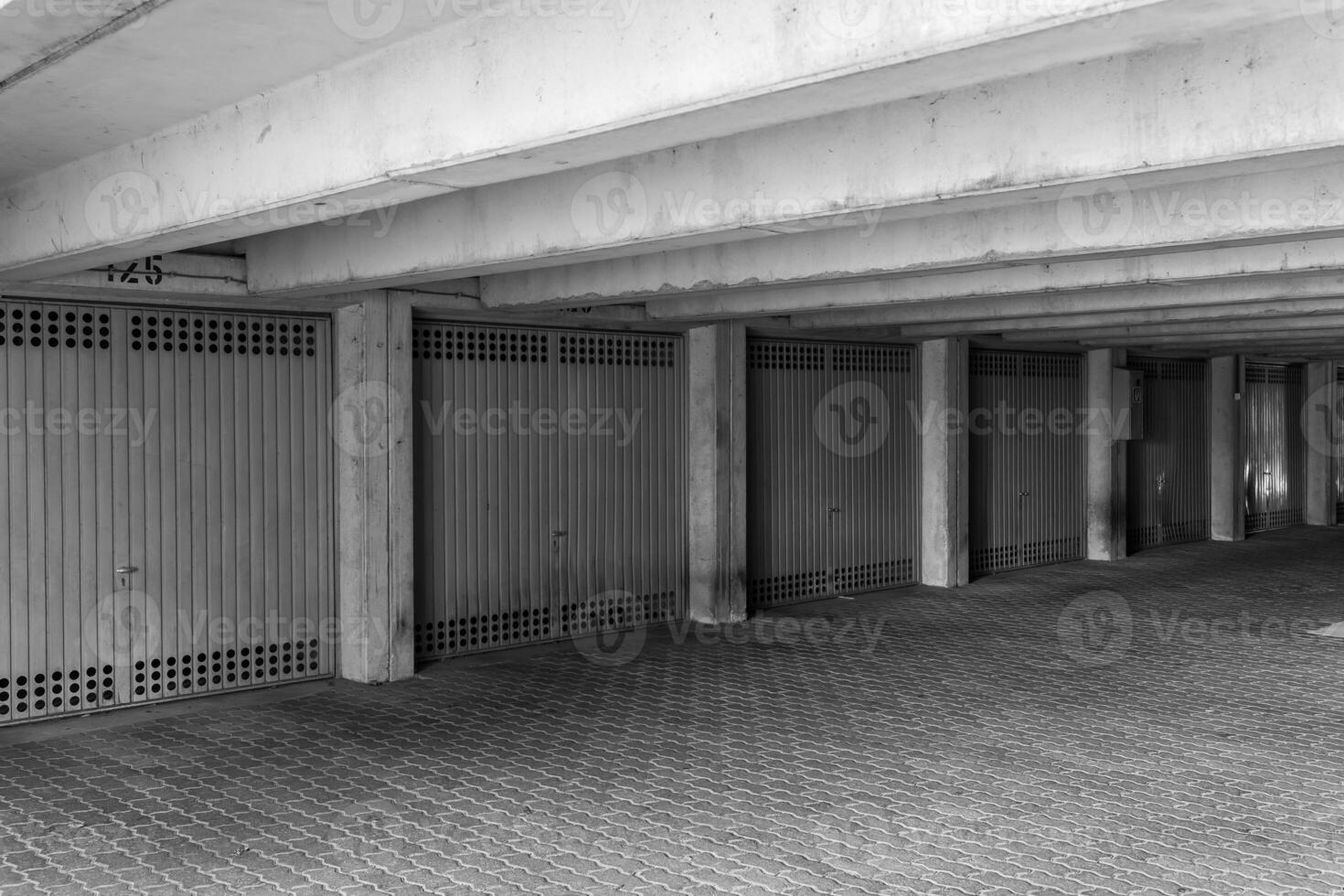 Concrete parking garage with closed doors and patterned flooring in urban setting during daylight hours photo
