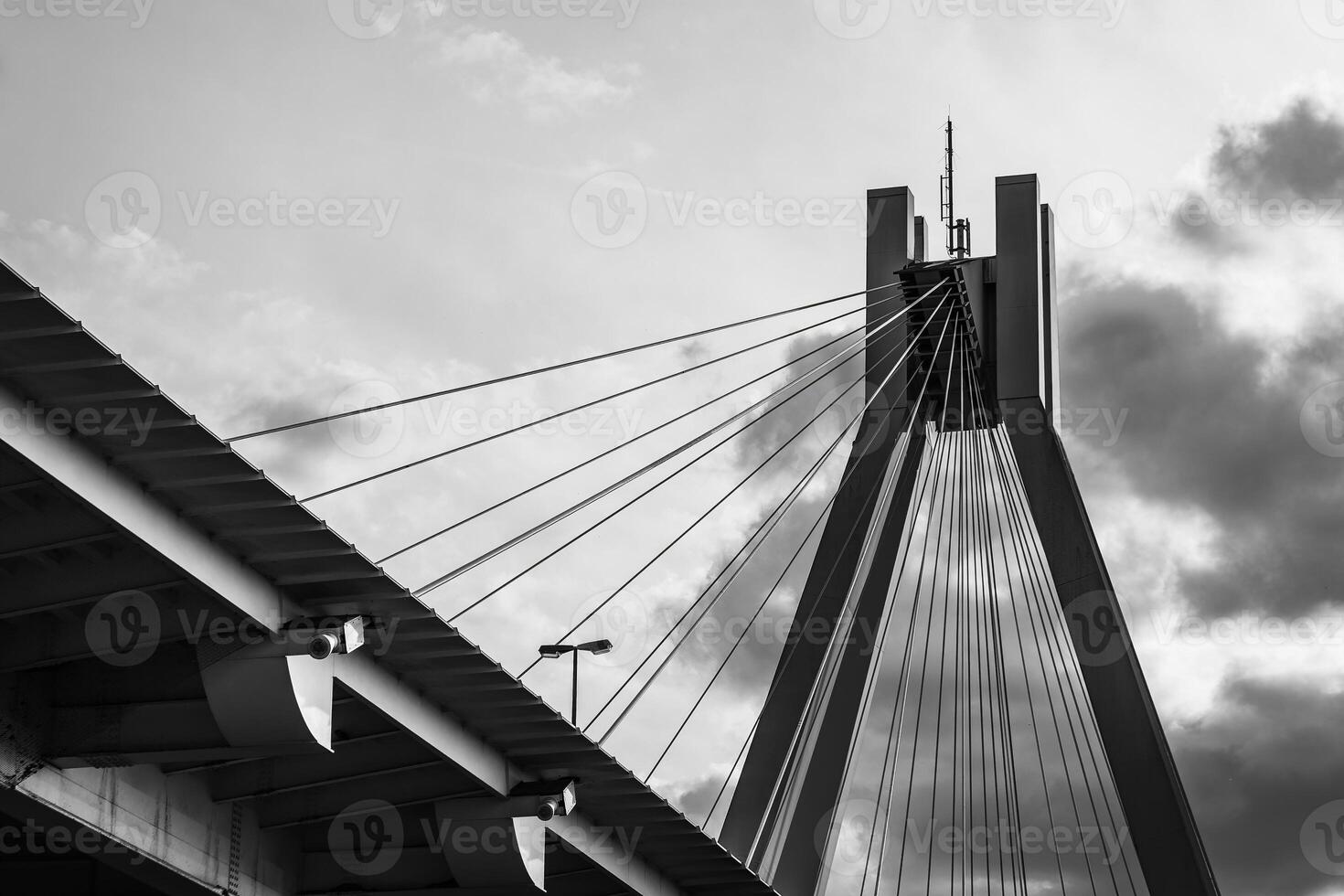 Suspension bridge towers under cloudy sky at sunset with cables and structural details highlighted photo