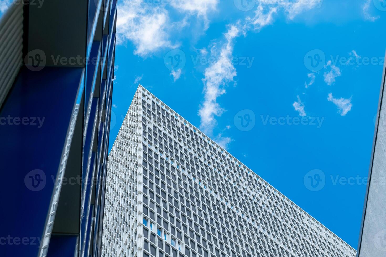 Modern architectural design showcases geometric patterns under a bright blue sky with clouds photo