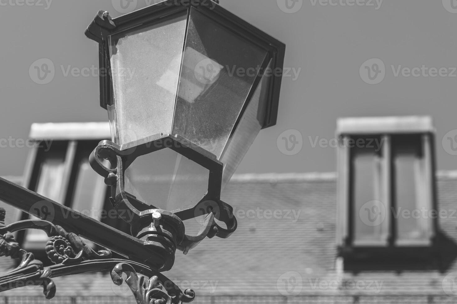 Urban street lamp illuminated against a vintage building in black and white photo