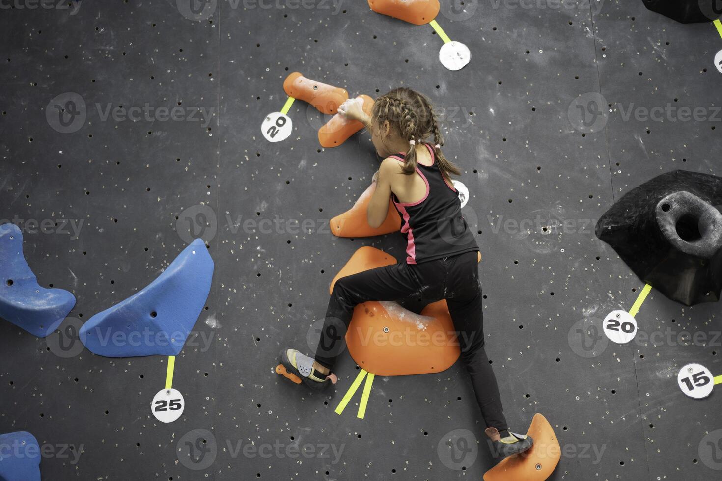 Determined girl climbing artificial rock wall at bouldering gym photo