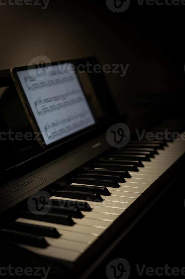 Black and white keys of an electric piano and a tablet screen, Selective focus photo
