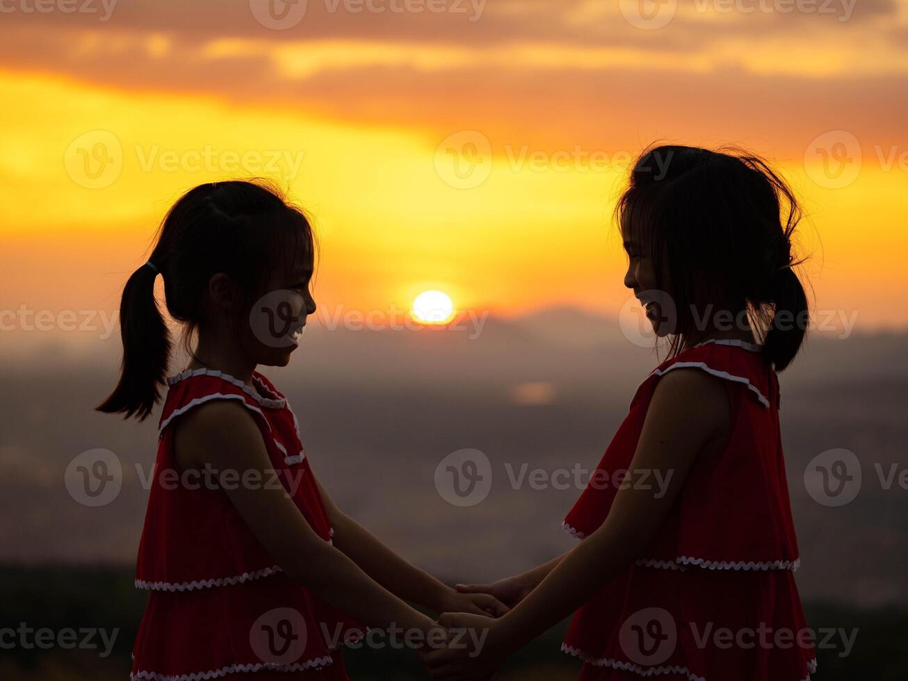 Silhouette of two little girls holding hands on a summer sunset background. Family love with colorful. photo