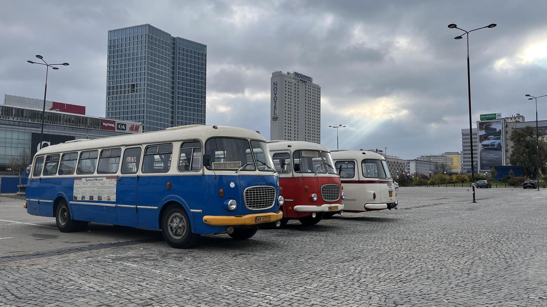 Warsaw, Poland. November 01, 2024. Three vintage buses parked in a row in a city setting. The buses are different colors blue, red, and white. They have a classic design with rounded edges and large photo