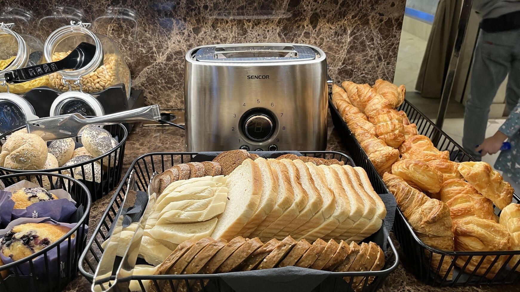 Vilnius, Lithuania. January 04, 2025. Freshly baked breads and pastries on a breakfast buffet includes sliced white bread, croissants, and other baked goods, ready to be enjoyed in a hotel restaurant photo