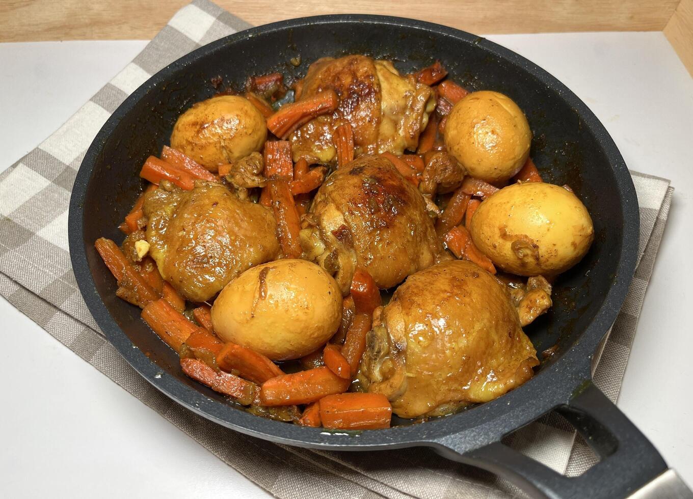 Delicious Ayam Kecap or Indonesian style sweet soy sauce chicken with carrots and hard-boiled eggs, served in a black pan. Perfect for recipes, articles, catalogs or any commercial purpose. photo