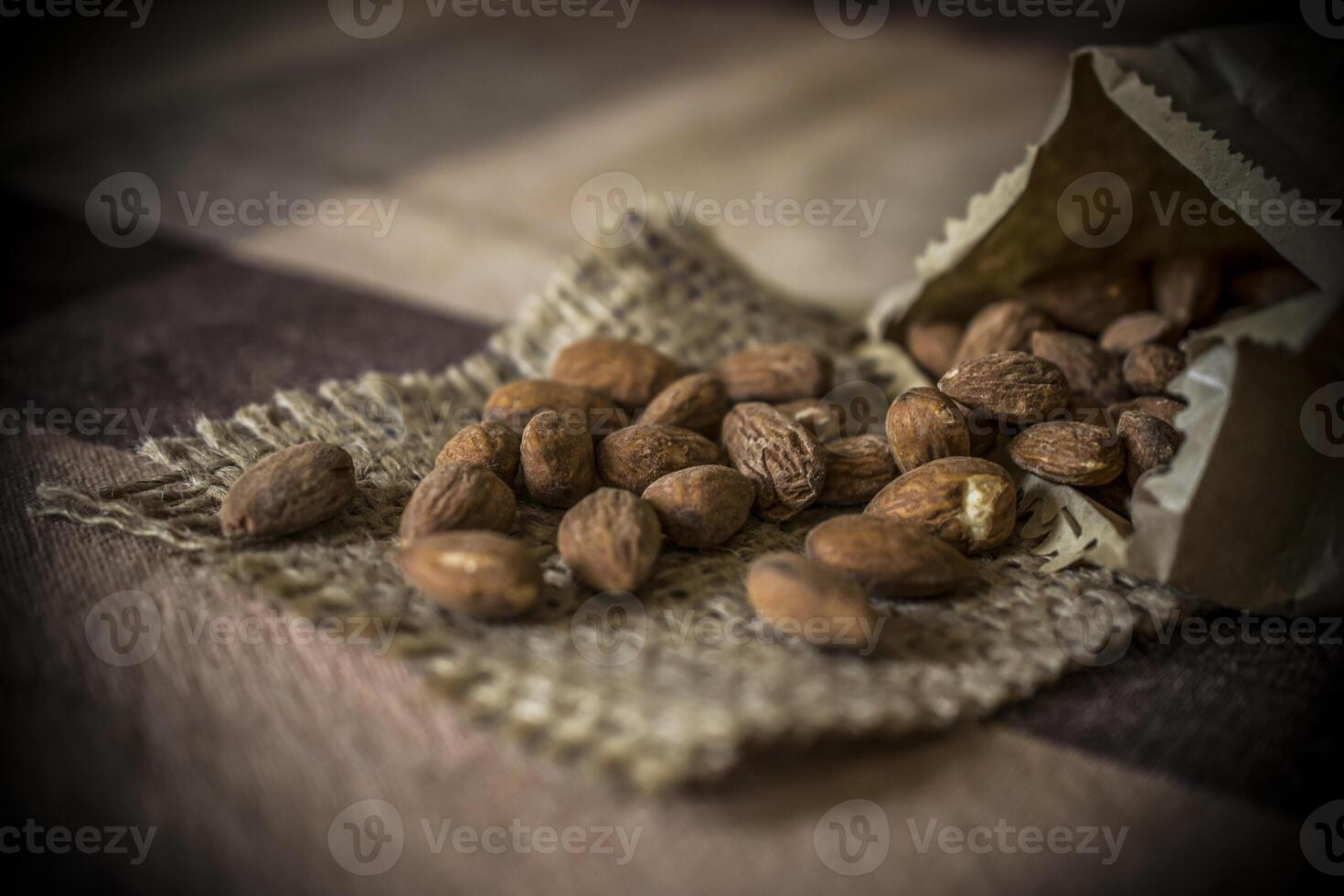 A heap of tasty almonds in a bag on a wooden table photo