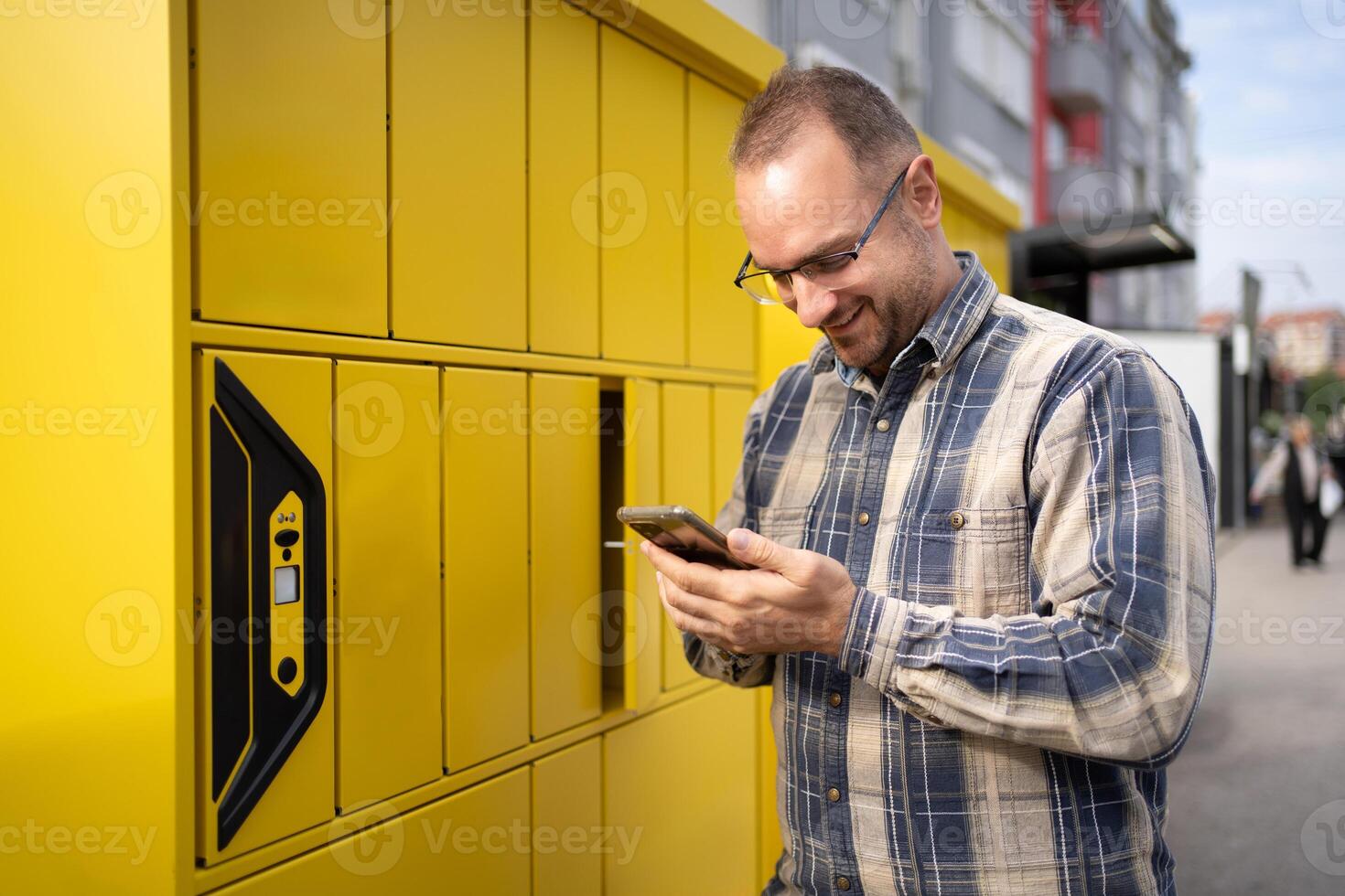 Happy man collects package from bright yellow locker in urban setting photo