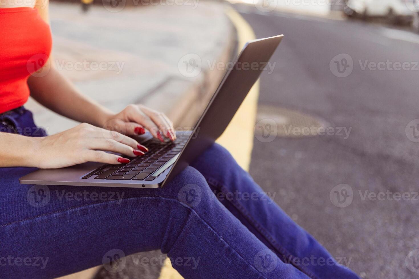 A woman is sitting on the ground with a laptop open in front of her photo