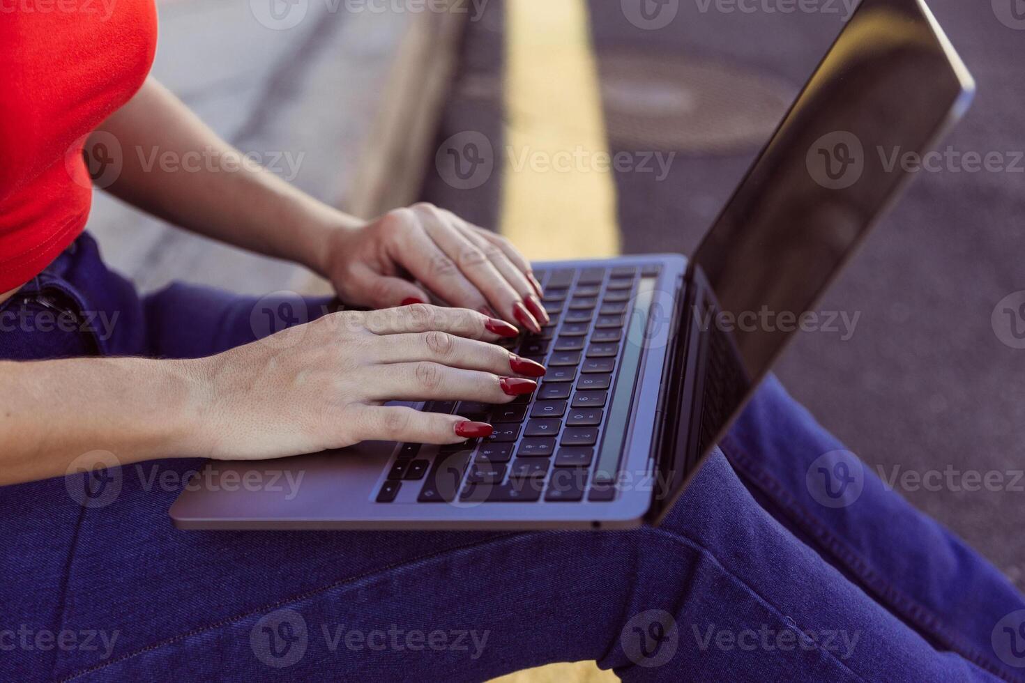 Close up of a woman's hands typing on a laptop while sitting on the ground photo