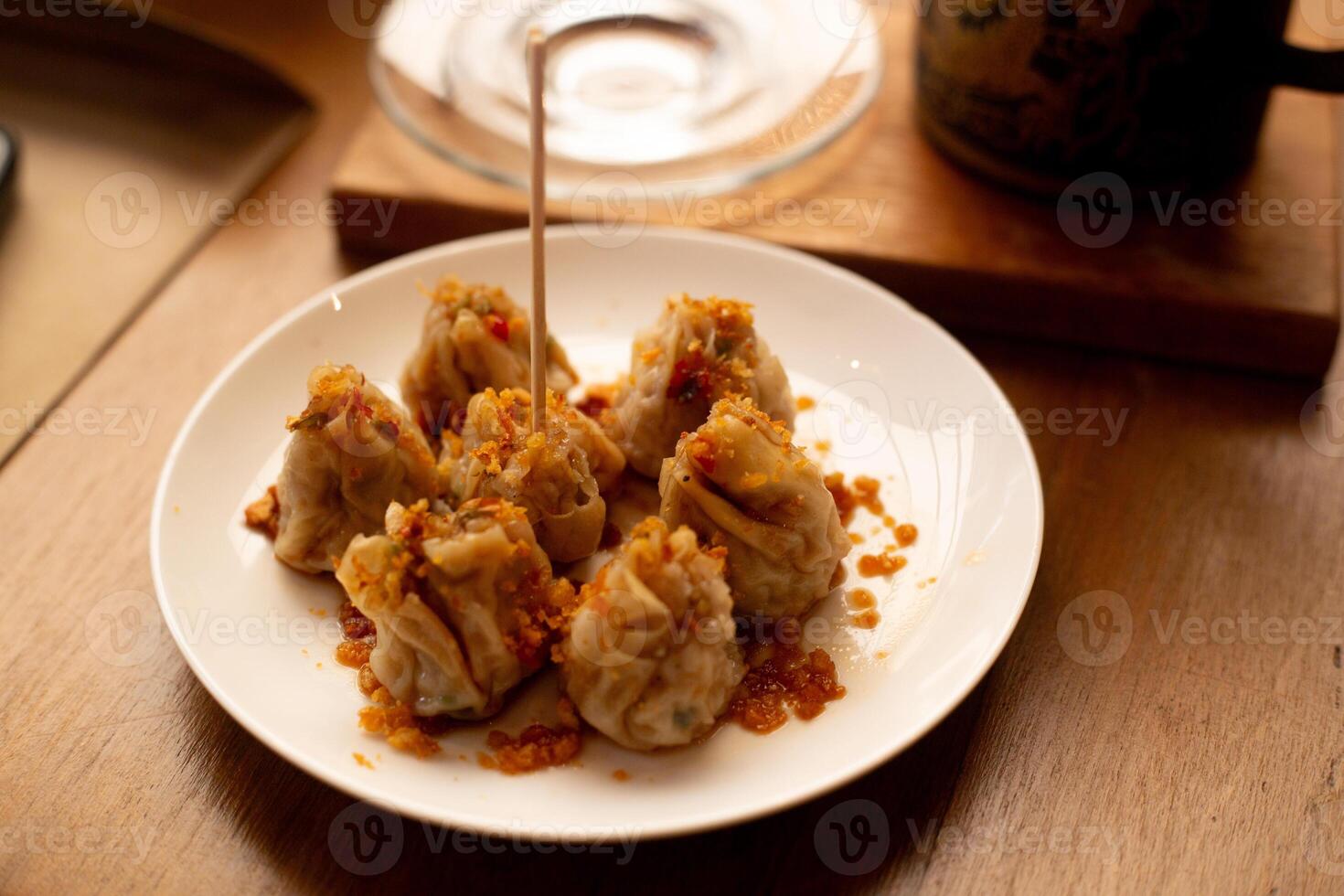 Chinese steamed dumplings top with braised leeks Fried garlic Served with a teapot wood tray and glass tea cup photo