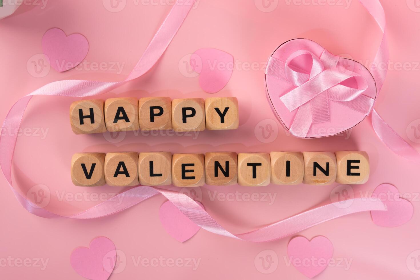 Wooden blocks spelling Happy Valentine next to a pink heart shaped gift box and pink ribbon. valentines day background concept photo