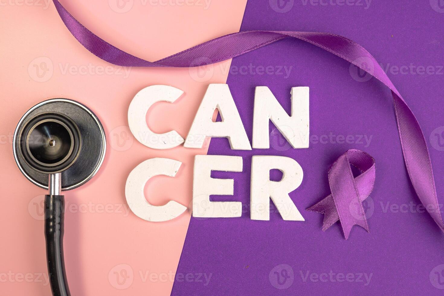 A stethoscope and purple ribbon next to the word CANCER. World cancer day concept photo