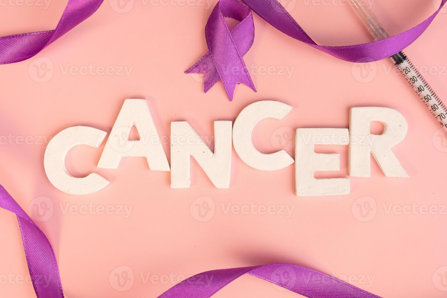 The word CANCER is spelled out in white letters surrounded by a purple ribbon and a syringe. Cancer awareness background photo