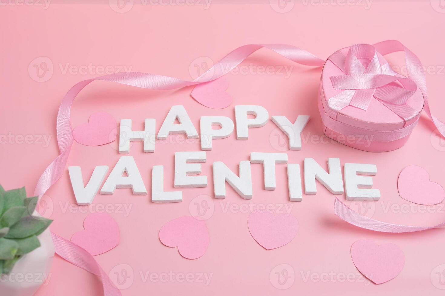 Happy Valentine spelled out with white letters surrounded by pink hearts and a pink heart shaped gift box photo