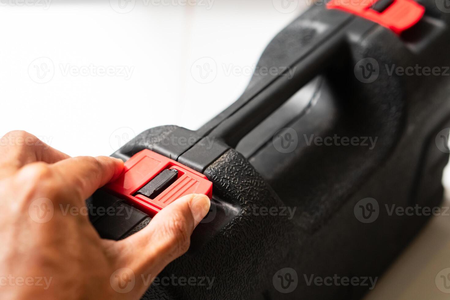 Hand Opening a Black Toolbox with Red Latches photo