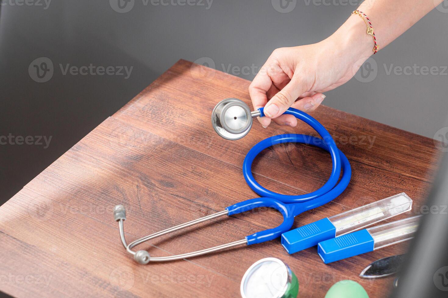 Hand Holding a Blue Stethoscope on a Wooden Table photo
