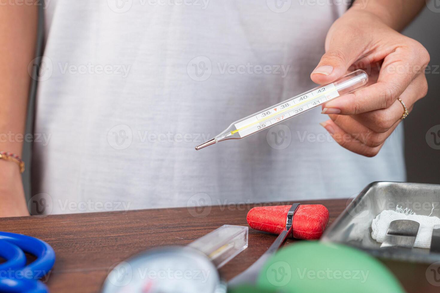 Person Holding a Thermometer with Medical Tools photo