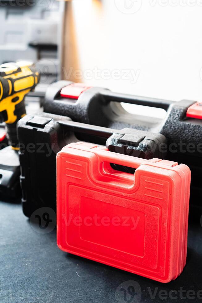 Red Tool Case Next to Black Toolbox and Yellow Drill photo