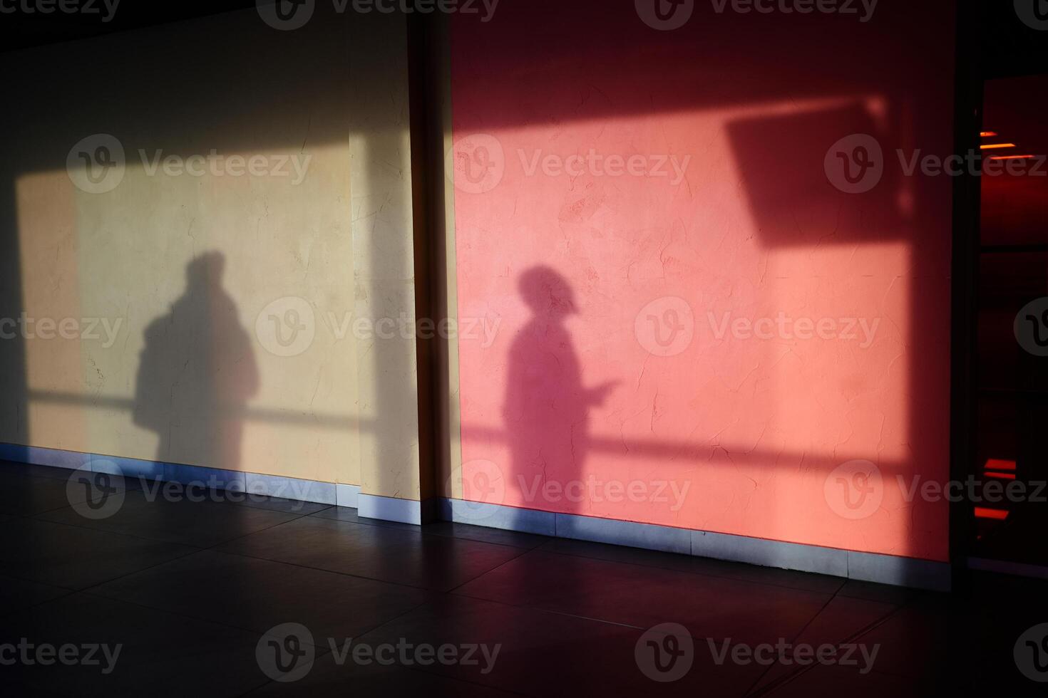 A shadow on the wall, a man watching the departures screen. Silhouettes of people with a reflection on the wall .The shadow of a man on a concrete wall, red in hue. photo