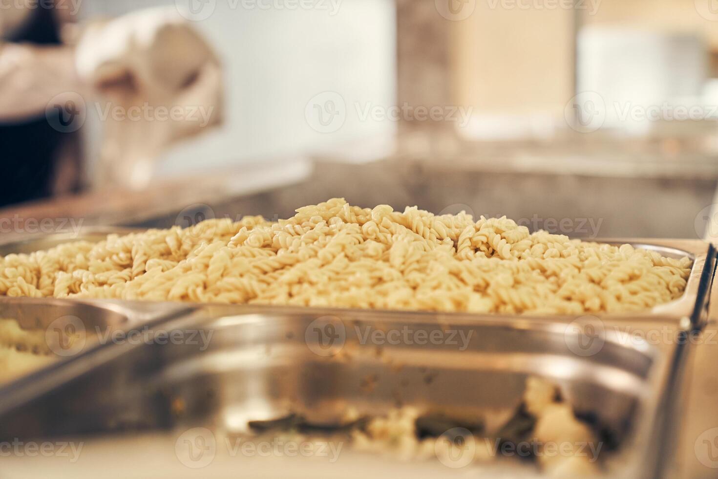 Self-service canteen at the training center. Close-up of boiled pasta on a metal tray photo