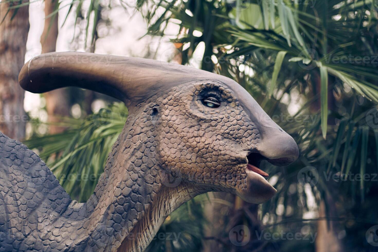 Dinosaur head close-up in the park. A giant parasaurolophus on display in the park on a sunny summer day with space to copy photo