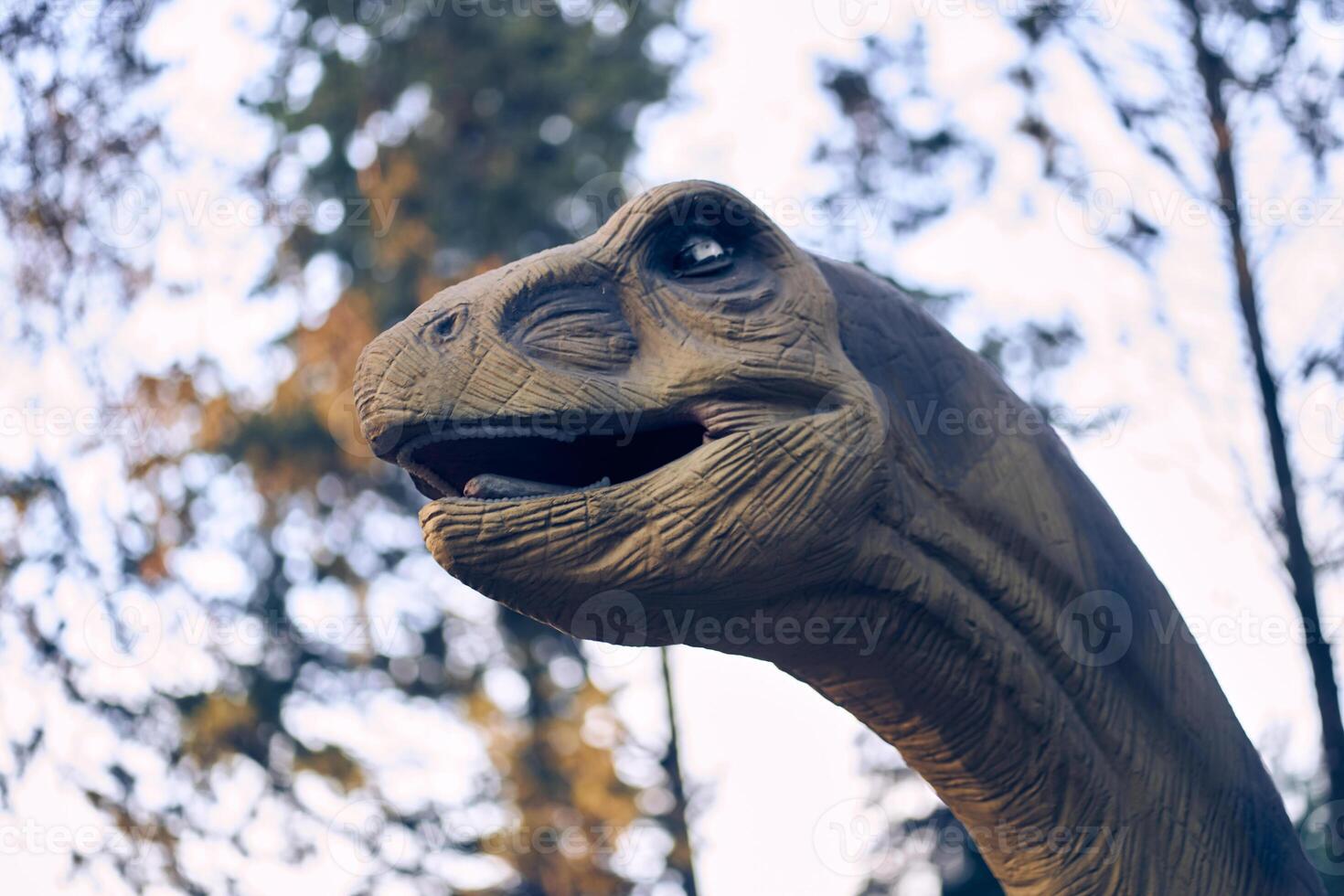 Against the background of trees is the head of a brachiosaurus, one of the largest and most popular. He lived at the end of the Jurassic period. There is a place to copy. photo