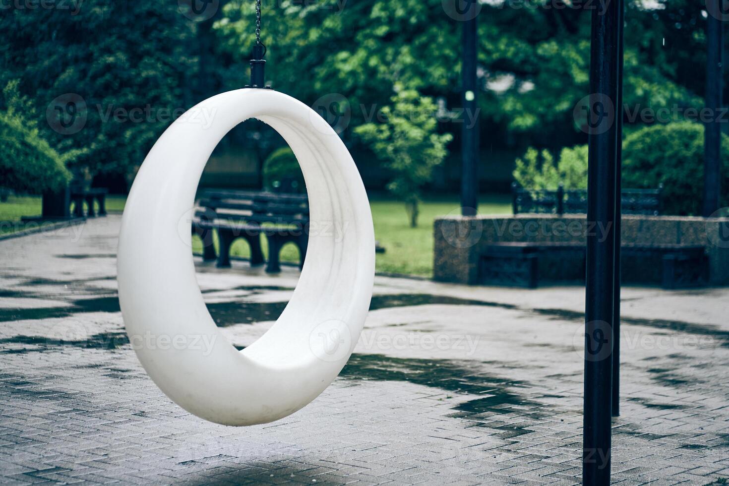 White round swing in cloudy weather. A recreation area in the park. Rocking chairs in the park in summer with space to copy photo