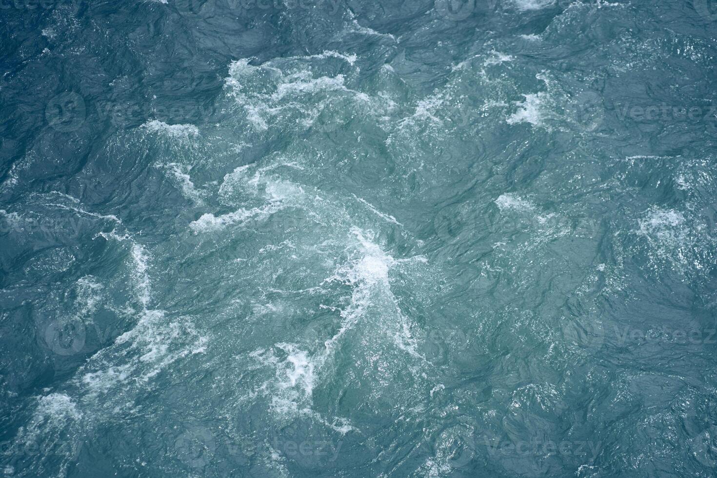 Beautiful background with blue water and a place to copy. Close-up of raging waters. Ripples and waves on the water. photo
