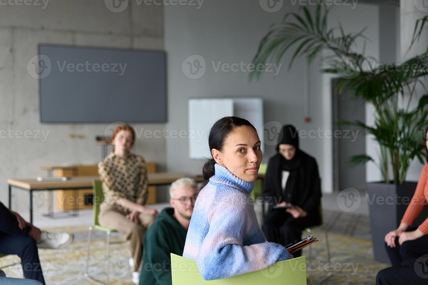 A diverse group of business professionals sits attentively in a modern office, actively participating in a training session led by an instructor, focusing on the latest technological advancements in photo
