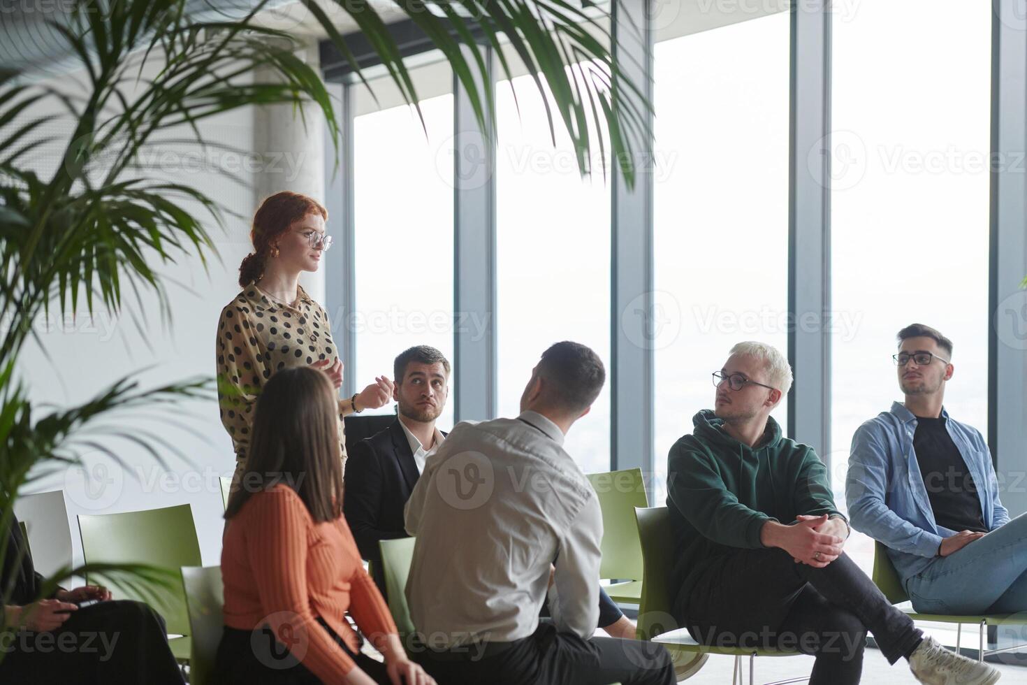 A diverse group of business professionals sits attentively in a modern office, actively participating in a training session led by an instructor, focusing on the latest technological advancements in photo